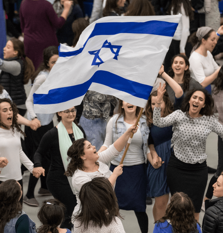Female students cheering and waiving the flag of Israel